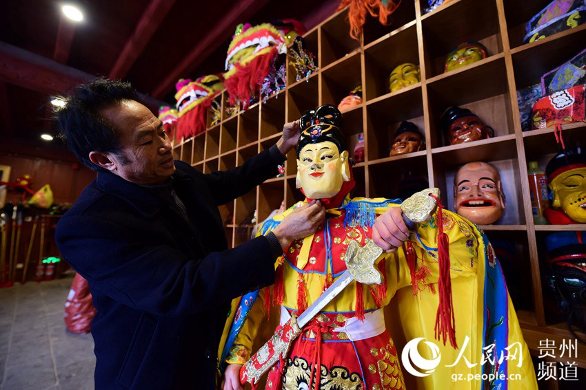 1月16日，福泉阳戏传承人周昌智（左）在为村民佩戴面具。