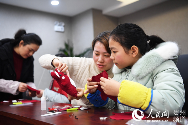 1月14日，貴州省貴陽市南明區小車河社區的一名小朋友正在和家人一起合作制作鼠年屬相布偶。