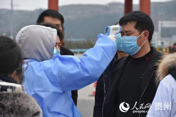 醫務工作人員對旅客進行體溫檢測。安順經開區融媒體中心供圖