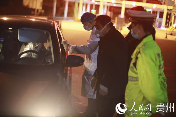 2月3日，貴州省畢節市黔西縣雨朵鎮大海子收費站卡口的工作人員夜間給車內人員測量體溫。陳德榮 攝