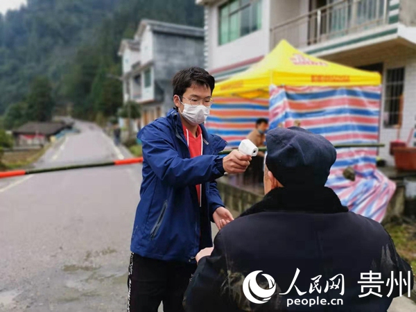 木江村村民楊明在監測點為過往村民測量體溫  。黃玉凡 攝