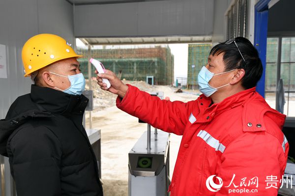 2月17日，在南明電子信息產業園內，一疫情防控工作人員正在對進行施工現場的工人進行體溫檢測。趙鬆 攝