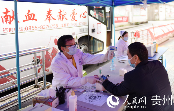 血站工作人員給參加獻血的職工測量體溫。