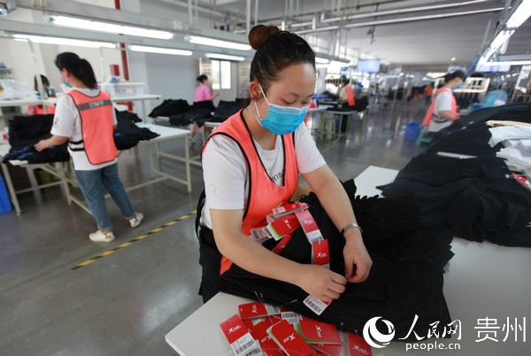 2020年5月7日，貴州省畢節市黔西縣岔白工業園區一家服裝企業的扶貧車間，員工為加工好的服裝上牌。 史開心 攝