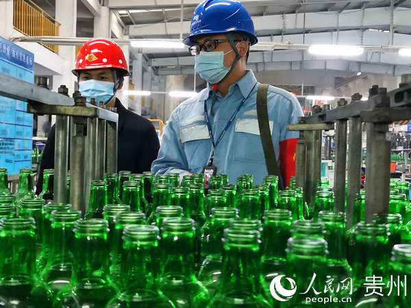 安順平壩供電局用電檢查人員與貴州華興玻璃廠車間負責人展開交流，詢問是否有用電方面的困難。譚鎮林 攝