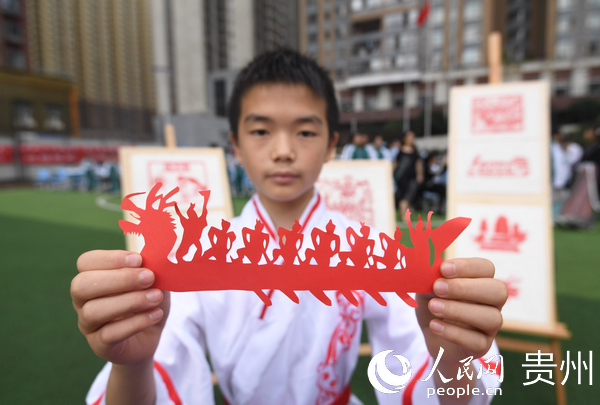 6月23日，貴州省貴陽市南明區第一實驗中學的一名同學展示自己的龍舟剪紙作品。