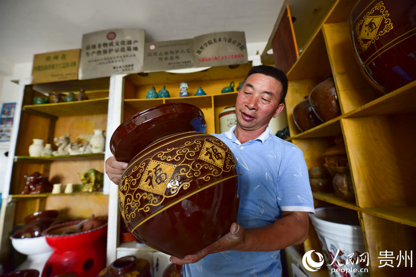7月4日，張忠祥在自己的土陶作坊裡展示制作的陶器。