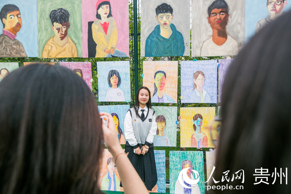 7月4日，學生正在貴州省畢節市民族中學足球場上觀賞劉一歌繪制的肖像油畫作品。