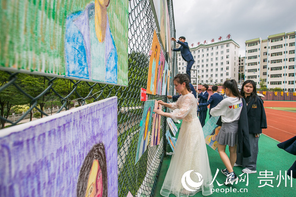 7月4日，學生正在貴州省畢節市民族中學足球場上將劉一歌繪制好的肖像油畫挂起來。