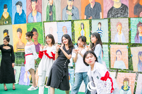7月4日，學生正在貴州省畢節市民族中學足球場上觀賞劉一歌繪制的肖像油畫作品。