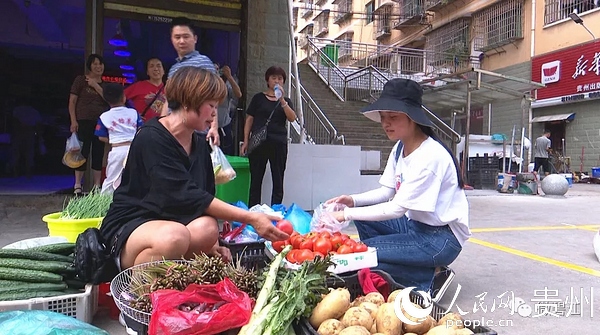 市民在摆放整齐的摊位前购买蔬菜。杨云 摄