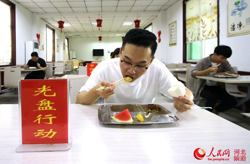8月12日，在河北省邯鄲市永年區供電公司職工餐廳，職工正在“光盤行動”提示牌前就餐。 胡高雷 攝