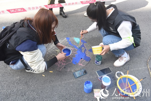 志願者以藍天白雲為底給井蓋繪制圖案
