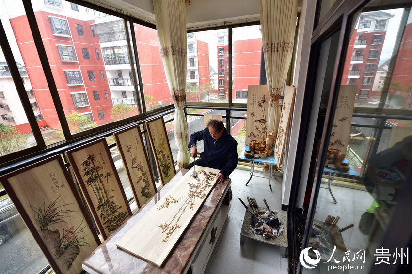貴州省丹寨縣金泉街道易地扶貧搬遷安置區，吳明章在家中創作烙畫。