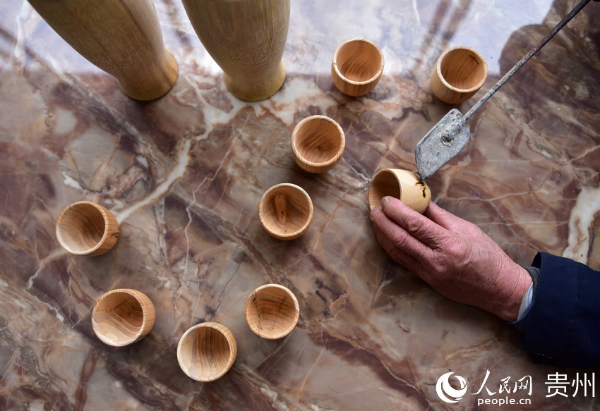 貴州省丹寨縣金泉街道易地扶貧搬遷安置區，吳明章在為好友制作的木質茶杯進行烙畫創作。