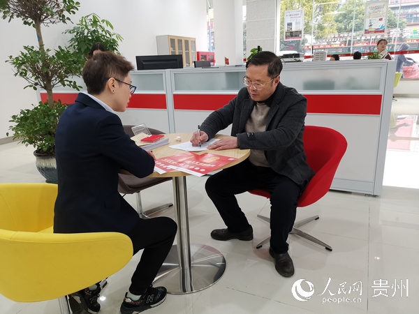 貴州銀行安順分行信貸客戶經理向小微企業主宣傳征信知識，簽訂貸款合同。