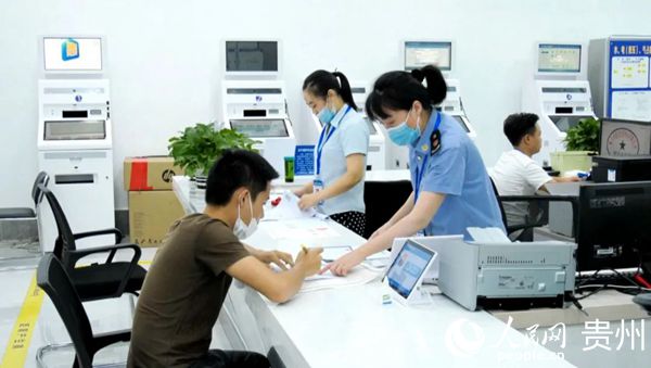 红花岗区政务服务大厅窗口工作人员正在指导群众填写相关表格。