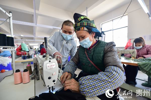 1月14日，在貴州省丹寨縣金鐘經濟開發區，龍明貴( 左一)在服裝加工車間指導工人加工服裝。