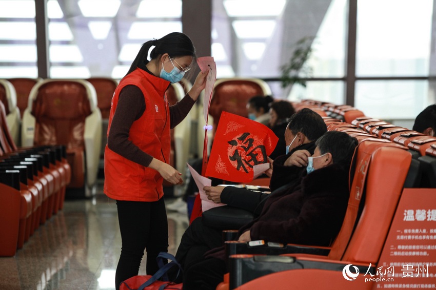 2月4日是農歷“小年”，畢節高鐵站內志願者送“福”給旅客。人民網 李宇 攝