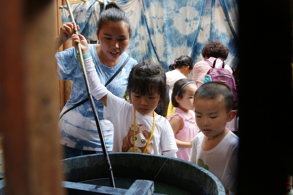 侗族婦女在指導小學生體驗藍靛水染的蠟畫作品。黎平縣委宣傳部提供