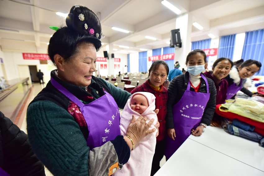 4月8日，在貴州省丹寨縣金泉街道易地扶貧搬遷安置區，搬遷群眾在練習嬰兒包單。