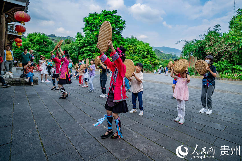 來肇興侗寨游玩的小朋友體驗侗族舞蹈。人民網 涂敏攝