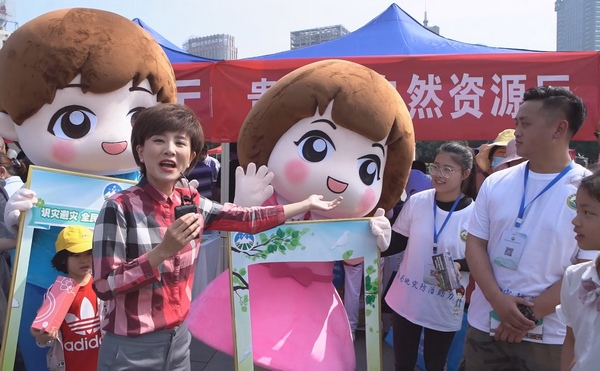 5月9日，记者冯聪在贵阳筑城广场的活动现场向大家介绍地灾防治工作的原创IP人物“平平和安安”。
