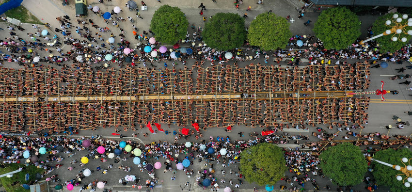 6月9日，在貴州省黔東南苗族侗族自治州施秉縣，千名群眾抬著木龍舟在縣城街道巡游（無人機照片）。