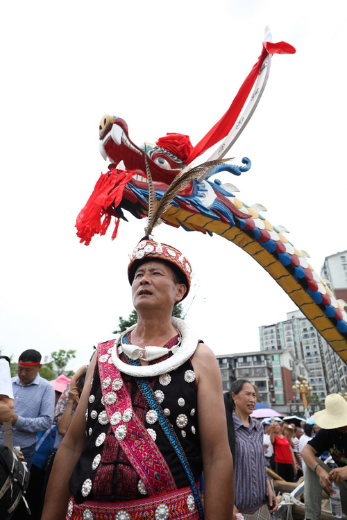 6月9日，在貴州省黔東南苗族侗族自治州施秉縣，一名身著節日盛裝的苗族群眾在木龍舟旁留影。