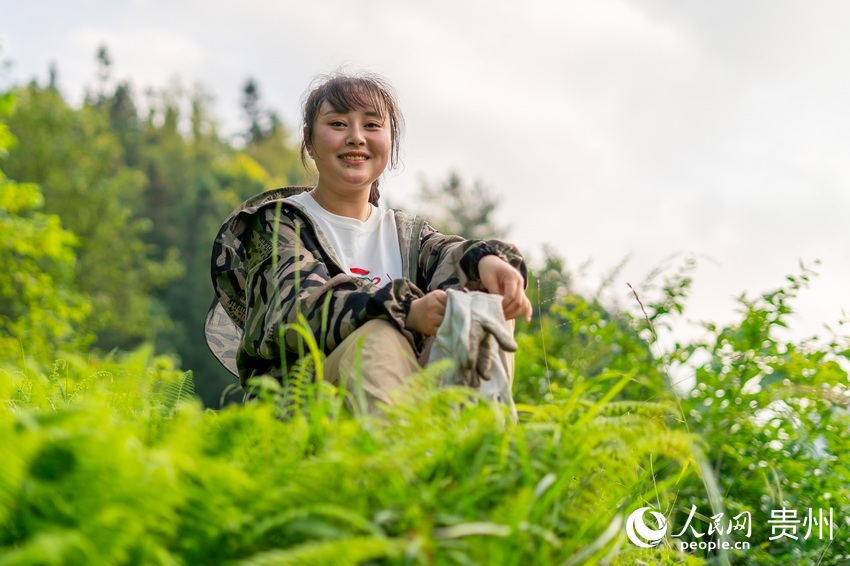 坐在山坡上看蜂箱的袁小梅。人民網 涂敏攝