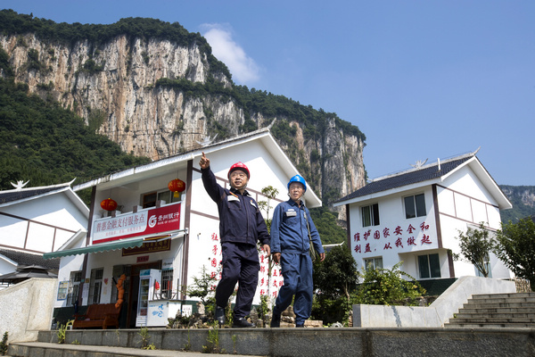 2021年8月4日,在贵州省黔西市新仁苗族乡化屋村易地扶贫搬迁安置点,马昌勇(左)和同事一起巡查电缆线路。