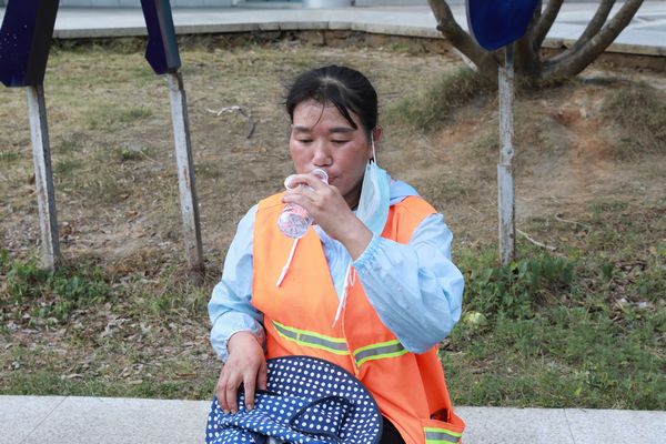 剑河县环卫工人杨明梅在路边喝水休息。杨婷摄
