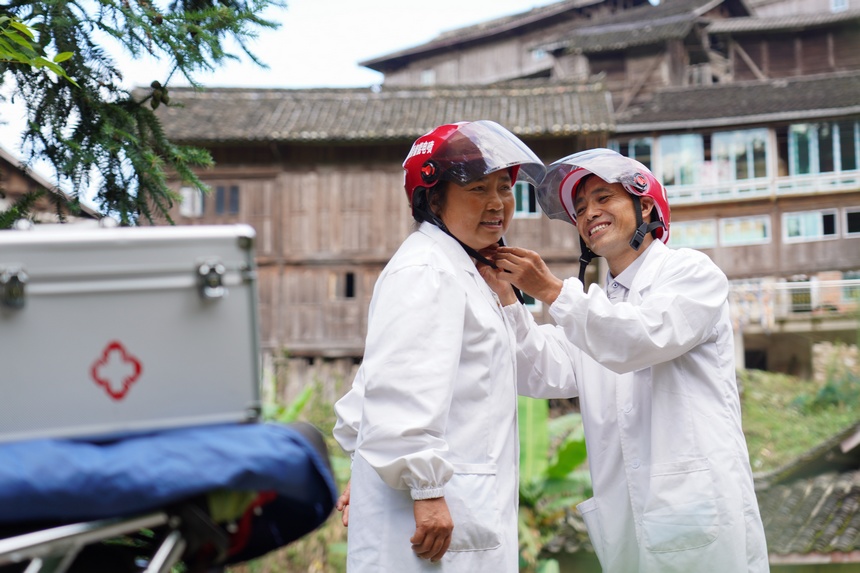 8月17日，在貴州省丹寨縣排調鎮黨早村，肖世軍（右）在出診前幫潘啟蘭整理摩托車頭盔。