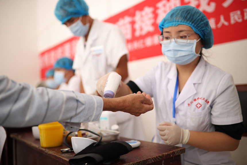 8月21日，在貴州省黔東南苗族侗族自治州丹寨縣興仁鎮翻仰村接種點，醫護人員對村民進行新冠疫苗接種前體溫測量。