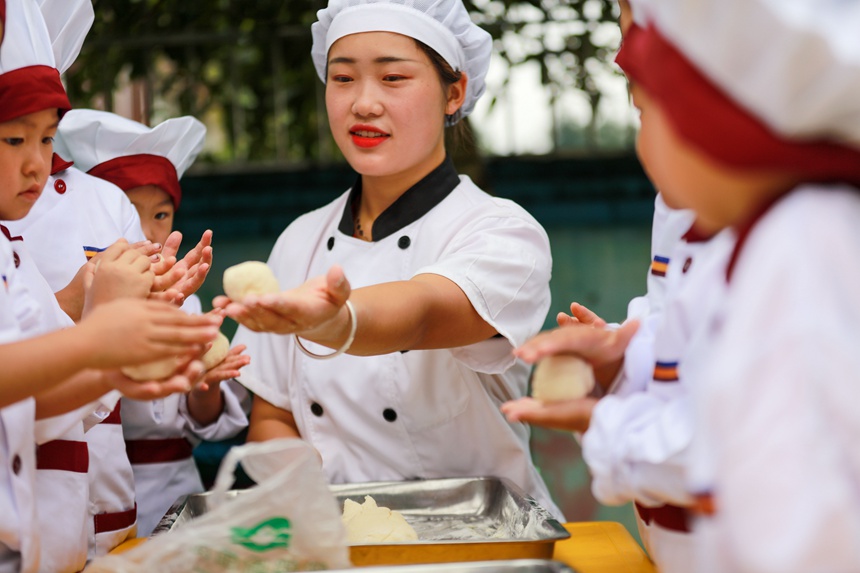 貴州省黔西市雨朵鎮金鑰匙幼兒園的老師和小朋友正在制作中秋月餅。
