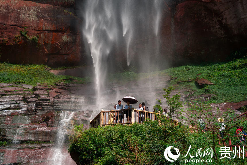 游客在“中國丹霞”赤水世界自然遺產佛光岩景區內近距離感受懸崖飛瀑。人民網 涂敏攝