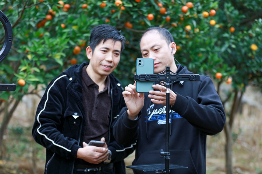 贵州省黔西市村村有货电商服务中心工作人员（右一）在该市素朴镇马路村指导村干部手机直播注册。