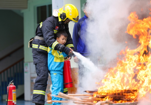 2021年11月9日，在贵州省铜仁市玉屏侗族自治县实验幼儿园，孩子们在体验消防设备的使用。