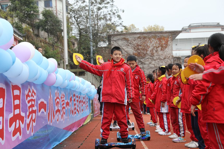 学生在贵州省贵阳市开阳县第一小学运动会开幕式上表演动感平衡车。