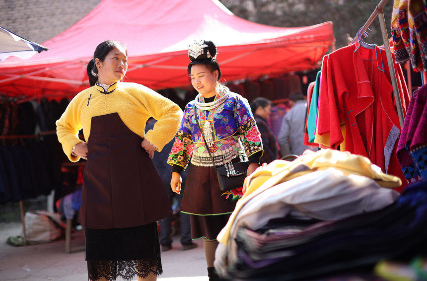 12月22日，苗族妇女在贵州省丹寨县县城集市上试穿传统苗族服装。