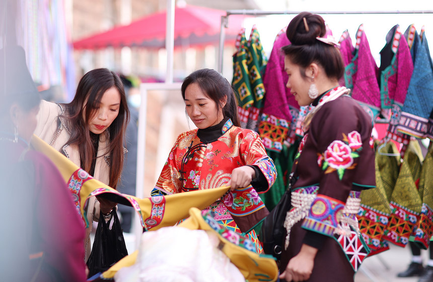 12月22日，苗族婦女在貴州省丹寨縣縣城集市上選購傳統苗族服裝。