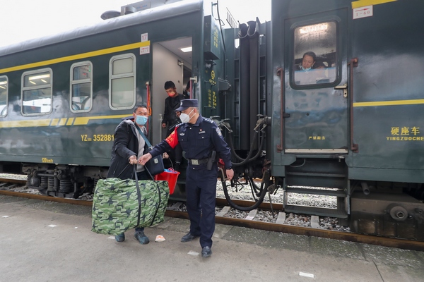 2022年1月8日，歐衛東（右一）在玉屏火車站幫助下車旅客提行李。