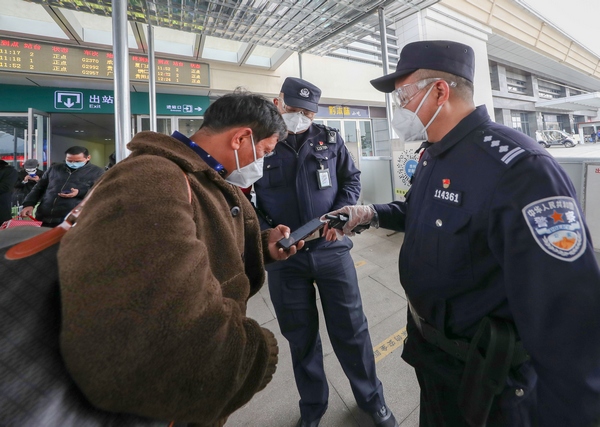 2022年1月9日，歐衛東（右一）在滬昆高鐵貴州銅仁南站出站口幫助旅客填寫“行程碼”信息。