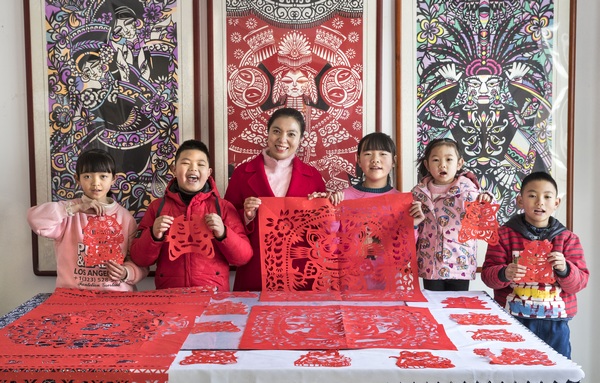 2022年1月18日，貴州省黔西市剪紙非遺傳承人岳紅霞（左三）在自己的工作室裡上公益課，和學生一起展示“剪虎迎新春”創作作品。