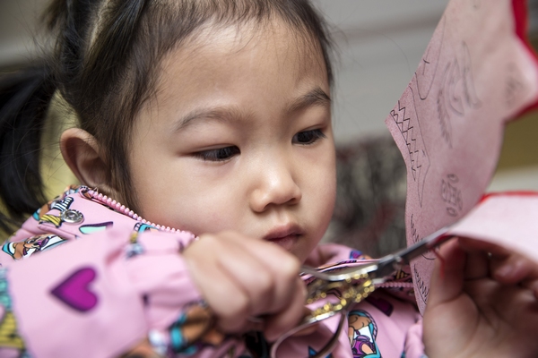 2022年1月18日，貴州省黔西市剪紙非遺傳承人岳紅霞在自己的工作室裡上公益課，一名小女孩進行“剪虎迎新春”創作。
