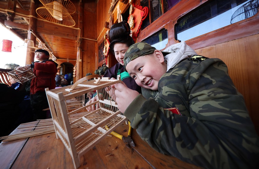 1月19日，小孩子在貴州省丹寨縣龍泉鎮卡拉村鳥籠制作技藝非遺傳習所學習編織鳥籠。