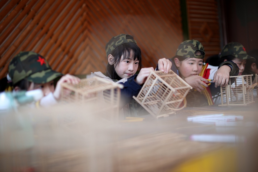 1月19日，小孩子在贵州省丹寨县龙泉镇卡拉村鸟笼制作技艺非遗传习所学习编织鸟笼。