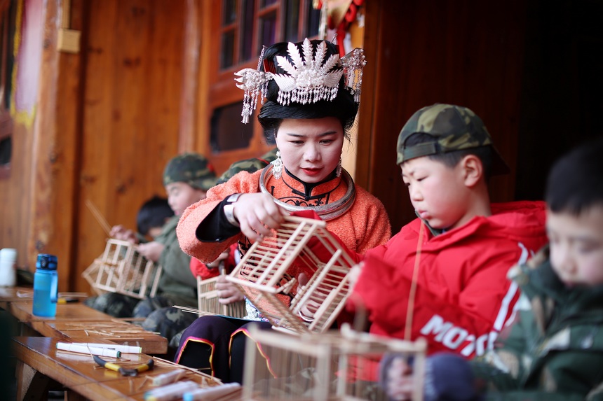 1月19日，在貴州省丹寨縣龍泉鎮卡拉村鳥籠制作技藝非遺傳習所，非遺傳承人在指導小孩子編織鳥籠。