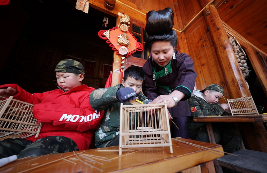 1月19日，在貴州省丹寨縣龍泉鎮卡拉村鳥籠制作技藝非遺傳習所，非遺傳承人在指導小孩子編織鳥籠。