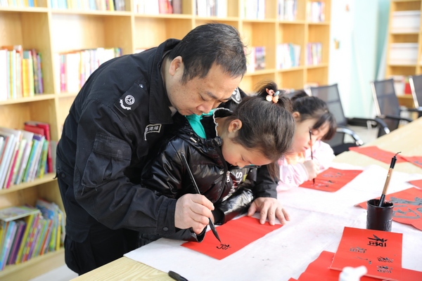 工作人员在教孩子们写福字。